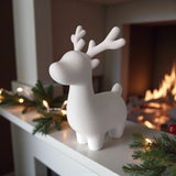 Minimalist Christmas reindeer sitting on a white windowsill with natural light