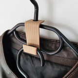 Minimalist hanger hook in use, organizing multiple coats together