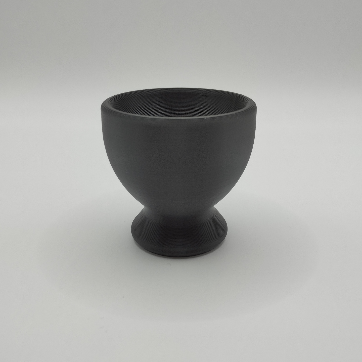 Two minimalist egg cups styled on a simple wooden table with fresh eggs