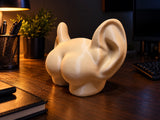 Røv med ører-pyntefigur set fra siden på et skrivebord