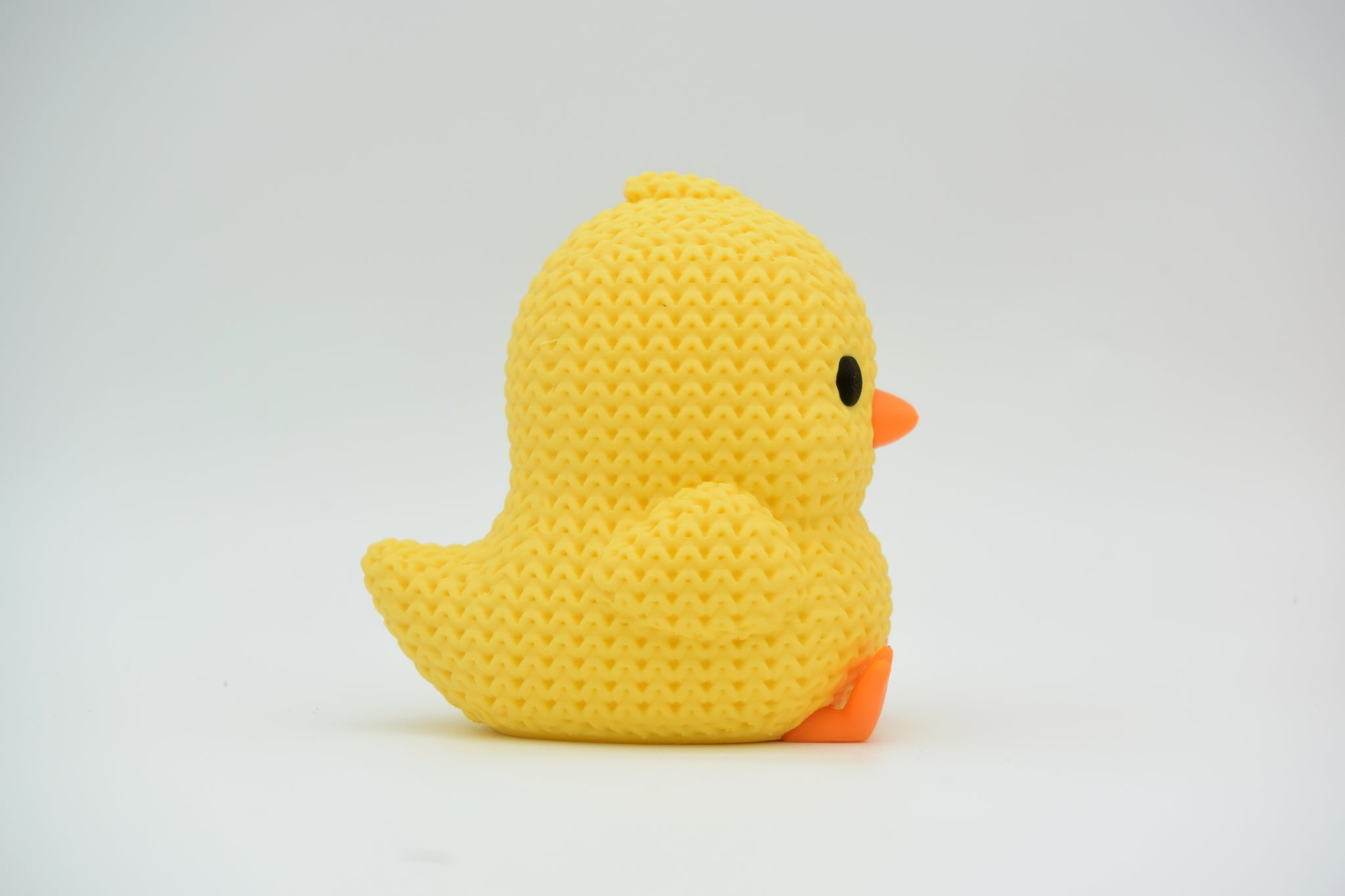 Knitted chick decoration styled on a wooden shelf with spring flowers and Easter ornaments