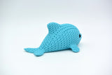 Close-up of a small knitted dolphin figurine with soft crochet-textured surface and round inset eyes