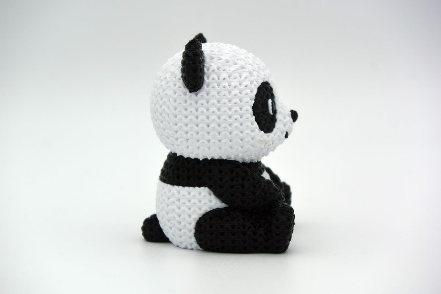 Close-up of a knitted panda figurine showing black and white crochet-look texture, small decorative object