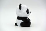 Close-up of a knitted panda figurine showing black and white crochet-look texture, small decorative object