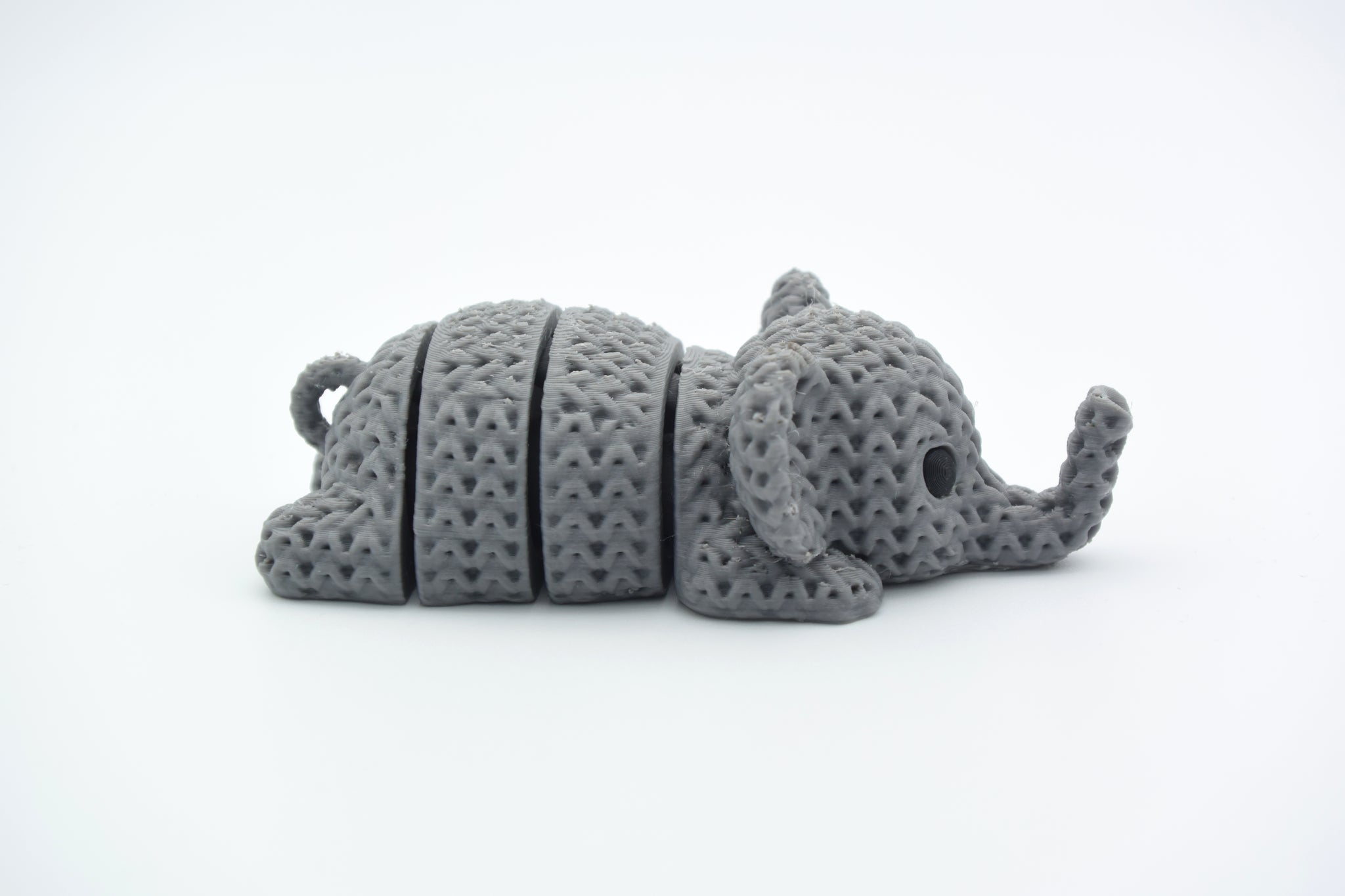 Small knitted elephant keychain resting on a wooden tabletop beside house keys and a linen pouch