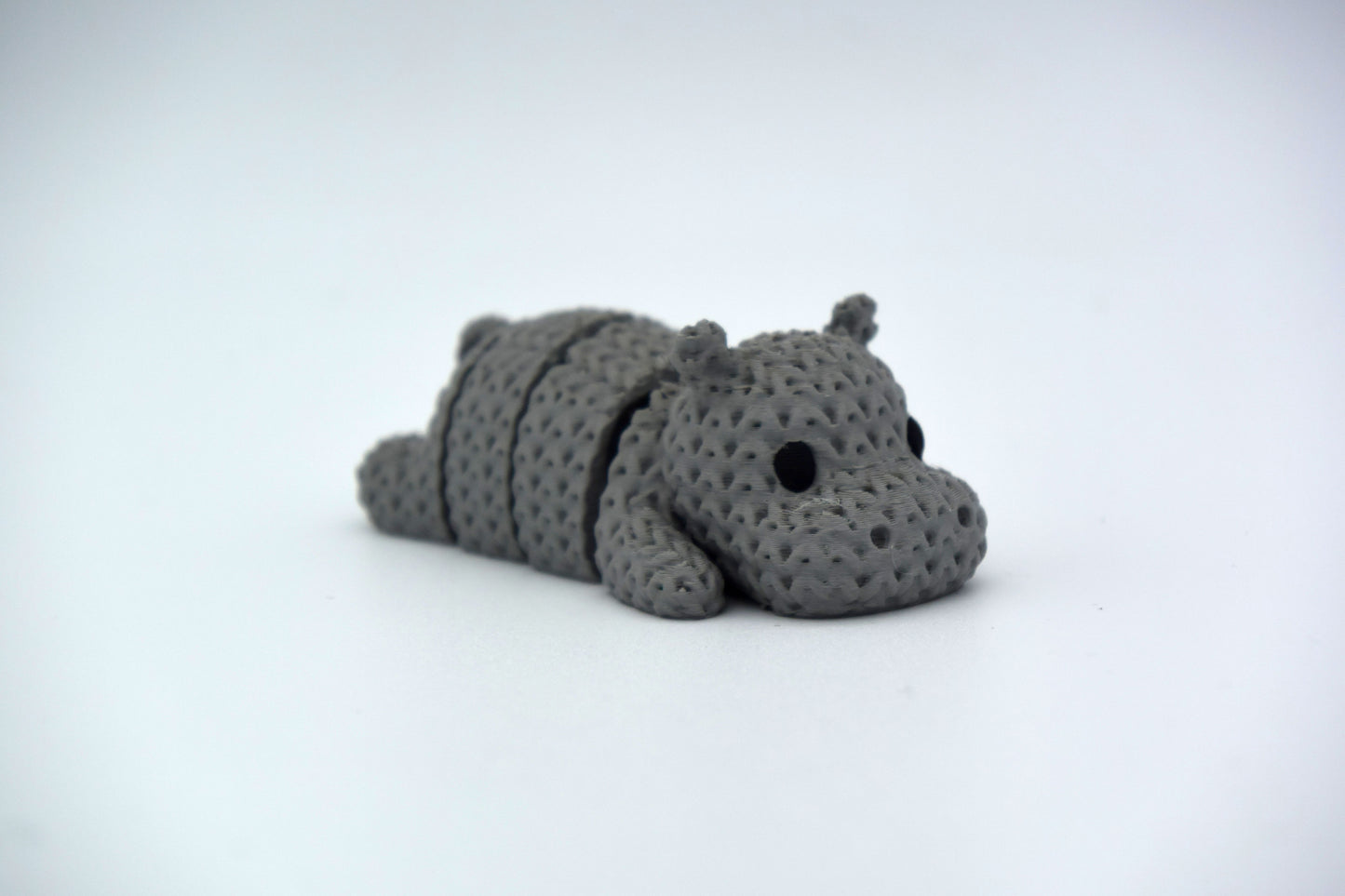 Close-up of a knitted hippo figurine with textured crochet-look surface, photographed on a white background
