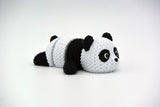 Knitted articulated panda figure in black and white with crochet-look texture, full body close-up on white background
