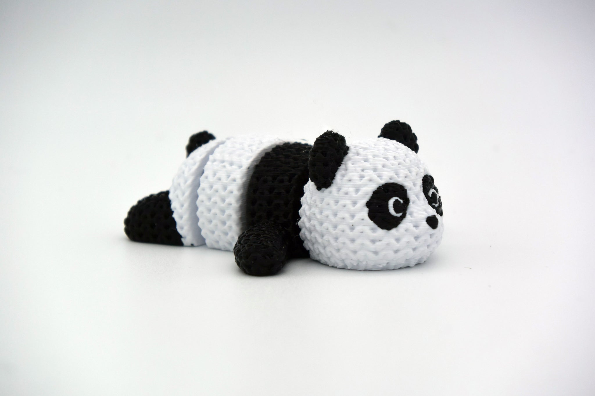 Knitted articulated panda figure in black and white with crochet-look texture, full body close-up on white background